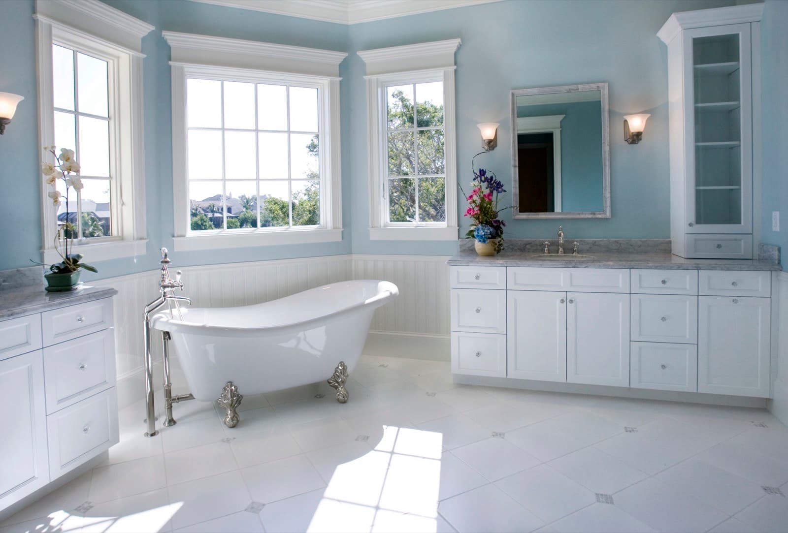 White clawfoot slipper tub with chrome feet in a bright blue bathroom