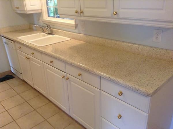 Kitchen countertop refinished in a speckled stone-fleck finish with white cabinets and double sink