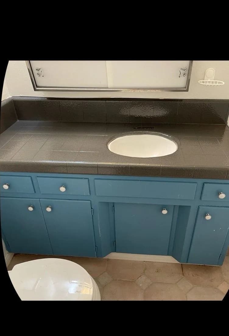 After: Vanity counter masked with plastic and blue tape beside the finished blue vanity with dark counter